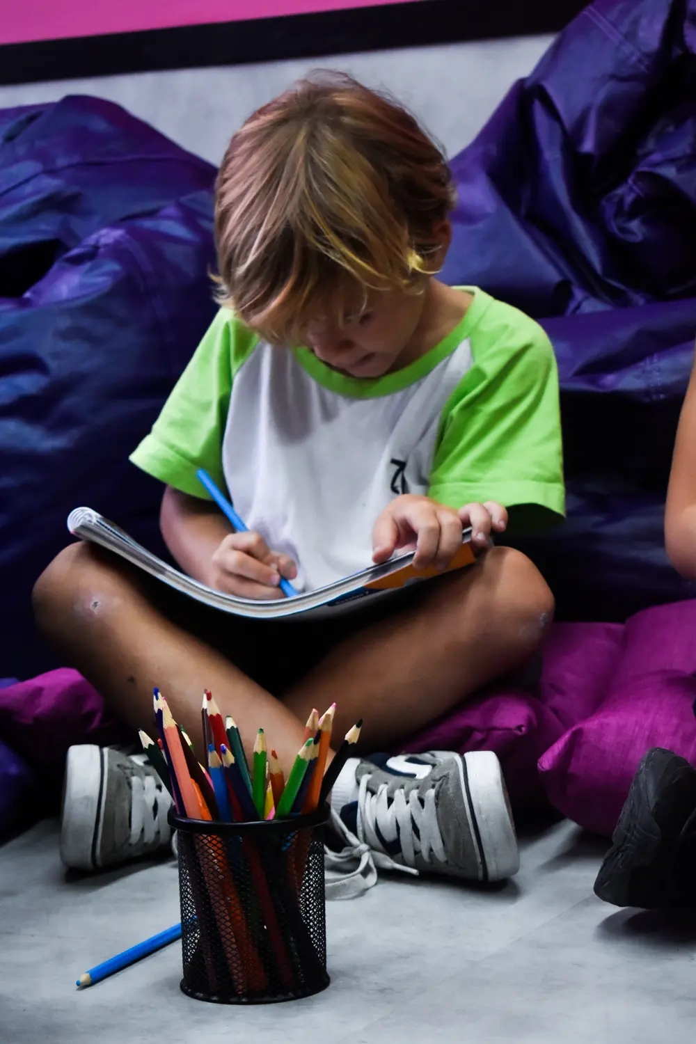 Aluno do Fundamental I desenhando no caderno no cantinho de leitura