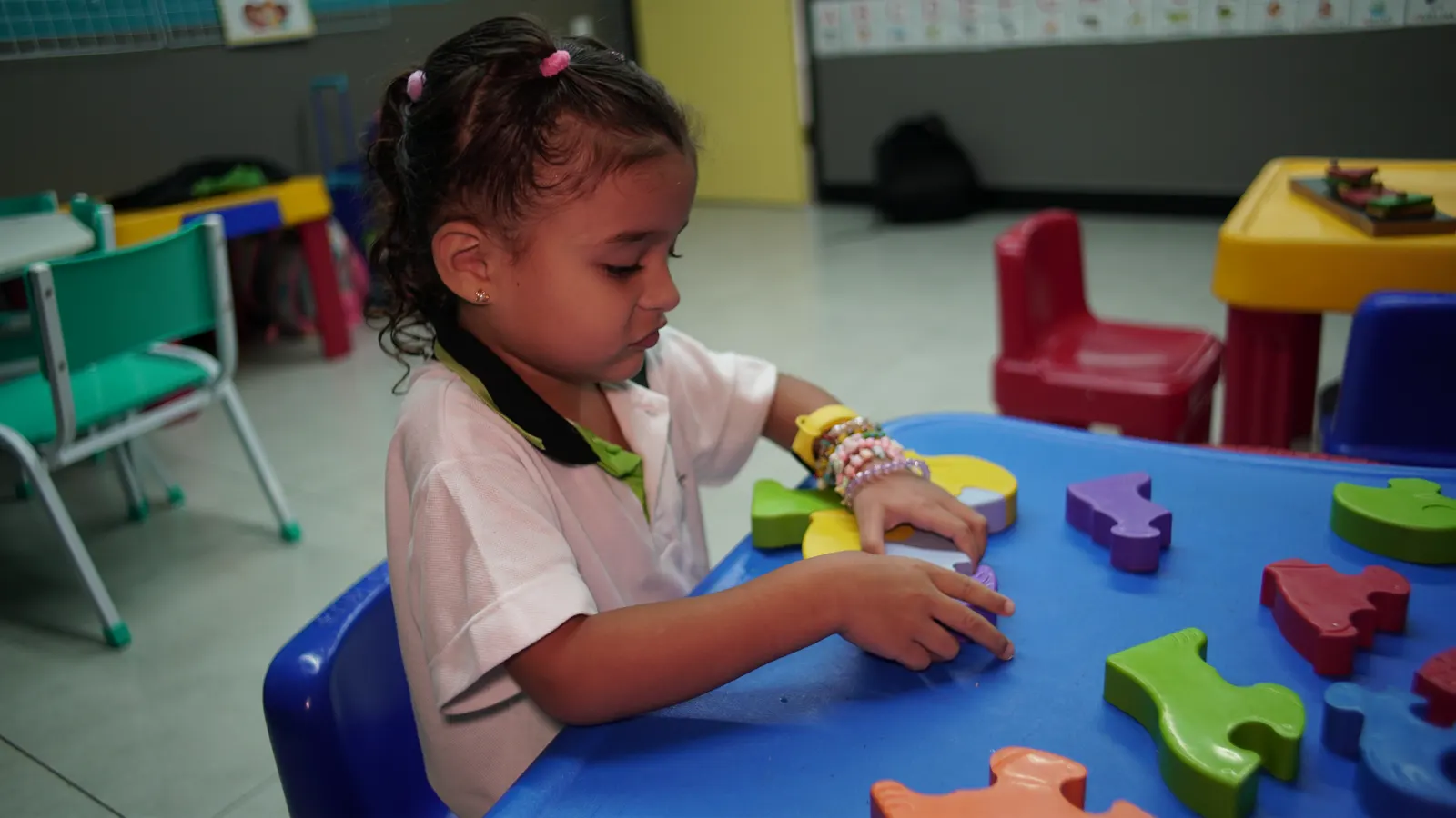 Aluna da Educação Infantil montando um quebra-cabeça de peças grandes e coloridas