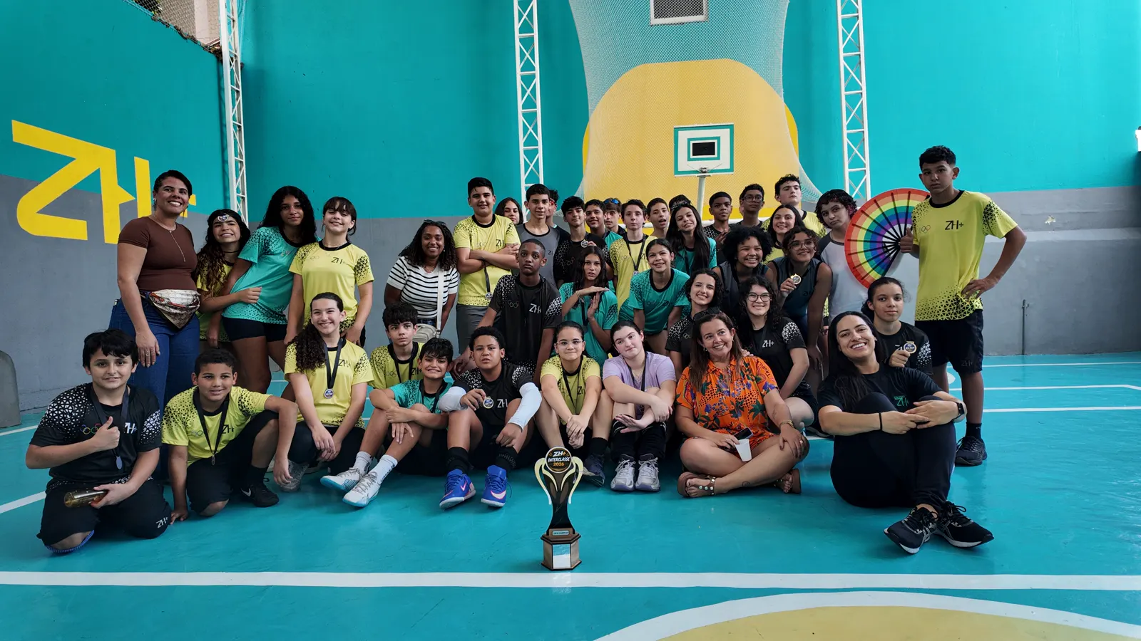 Alunos e professoras da unidade Méier reunidos na quadra com o troféu de um campeonato