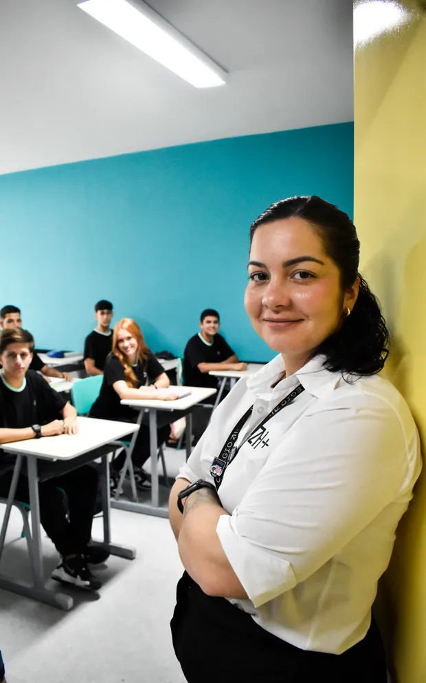 Professora em sala, com a turma ao fundo